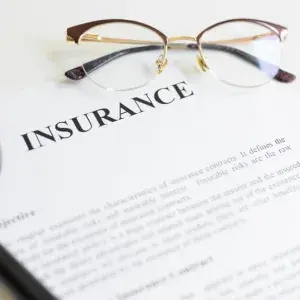 document that says insurance on top with glasses and a magnifine glass next to it